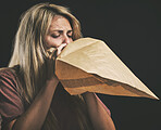 Anxiety, breathing and scared woman with paper bag, mental health and emergency oxygen air for lungs on black background. Panic attack breathe problem, stress and fear of depression, nausea and sick