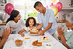 Child, birthday cake and celebration party with family and parents of a happy and excited girl ready to blow her candles at home. Cute kid at a table in her Puerto Rico house with balloons and snacks 
