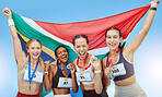 Portrait diverse group of female olympic athletes holding winners' medals and African flag. Happy and proud champions of South Africa. Winning a medal for your country is an amazing achievement