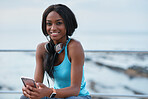 Young african american woman using smartphone on beach female jogger smiling happy sitting on bench relaxing by the sea