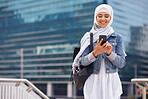 Young muslim woman using smartphone in city texting on mobile phone wearing traditional hijab headscarf