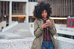 African american woman using smartphone in city wearing earphones listening to music with mobile phone