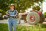 Farm, agriculture and tractor with a young woman farmer standing outside in the farming industry. Sustainability, organic and eco friendly agricultural harvest during summer or spring harvest season