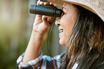 Nature, animal and bird watching of a smiling older woman looking and holding binoculars outside. Closeup of a mature female enjoying retirement relaxing on a day outdoors break feeling carefree