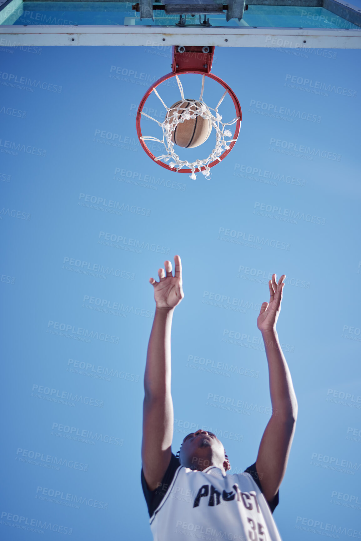 Buy stock photo Basketball jump, goal and man on court playing a game low angle for mock up. Motivation, fitness and healthy lifestyle mindset of athlete. Dedicated sports person outside with a blue sky background.