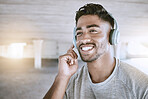 Workout music, fitness headphones or digital radio. Music technology device plays music, smiling relaxed indian man listening to audio sound earphone while exercising in city parking lot closeup.