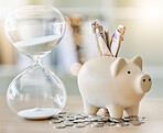 Money, finance and saving with a piggy bank and hourglass on a tablet or desk with time, cash and coins. Financial investment, retirement or planning for the future with a budget and growth strategy