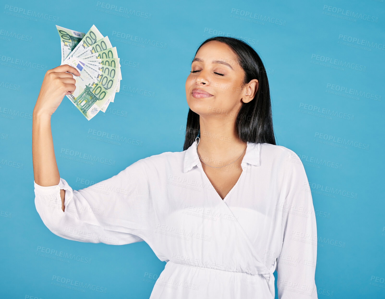 Buy stock photo Money, wealth and rich woman holding fan of cash and cooling herself, ready to blow or spend it all. Female lottery winner embracing luck, success and win in the studio on a blue background.