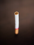 Closeup of a cigarette isolated on dark background. Stop smoking and quit bad habits like tobacco. Addiction is unhealthy and causes cancer. The tobacco industry has a dark side.