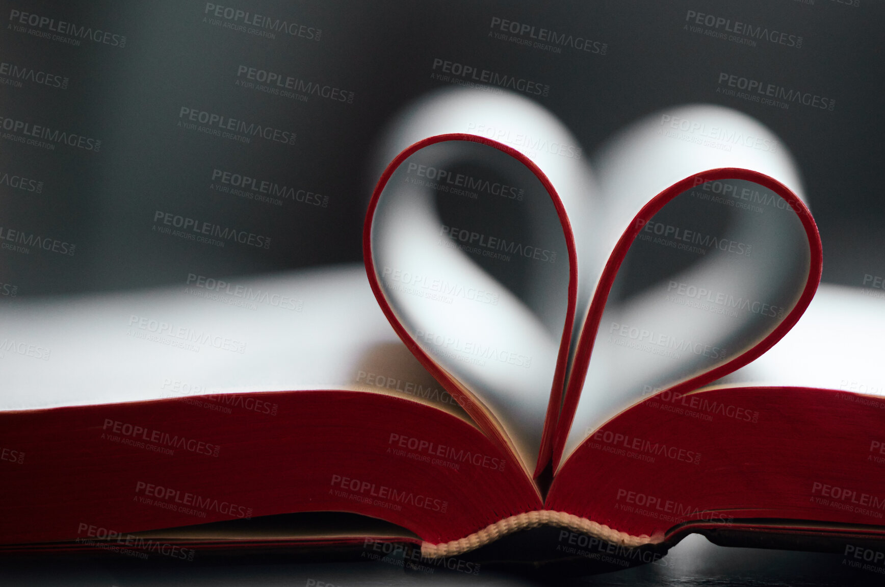 Buy stock photo Book, pages and fold with heart shape in closeup for reading, learning or literature by blurred background. Paper, icon and love story with emoji for education, knowledge and development at library