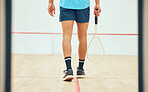Rear view of unknown squash player walking alone on court and holding racket before game. Fit active mixed race athlete getting ready for training and practice in sports centre. Sporty hispanic man
