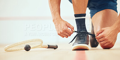Buy stock photo Unknown athletic squash player kneeling and tying shoelaces before playing court game with copyspace. Fit active caucasian athlete getting ready for training practice at sports centre. Sporty man