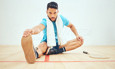 Full length of squash player stretching and looking focused before playing court game with copyspace. Fit active hispanic athlete sitting alone and getting ready for training practice in sports centre