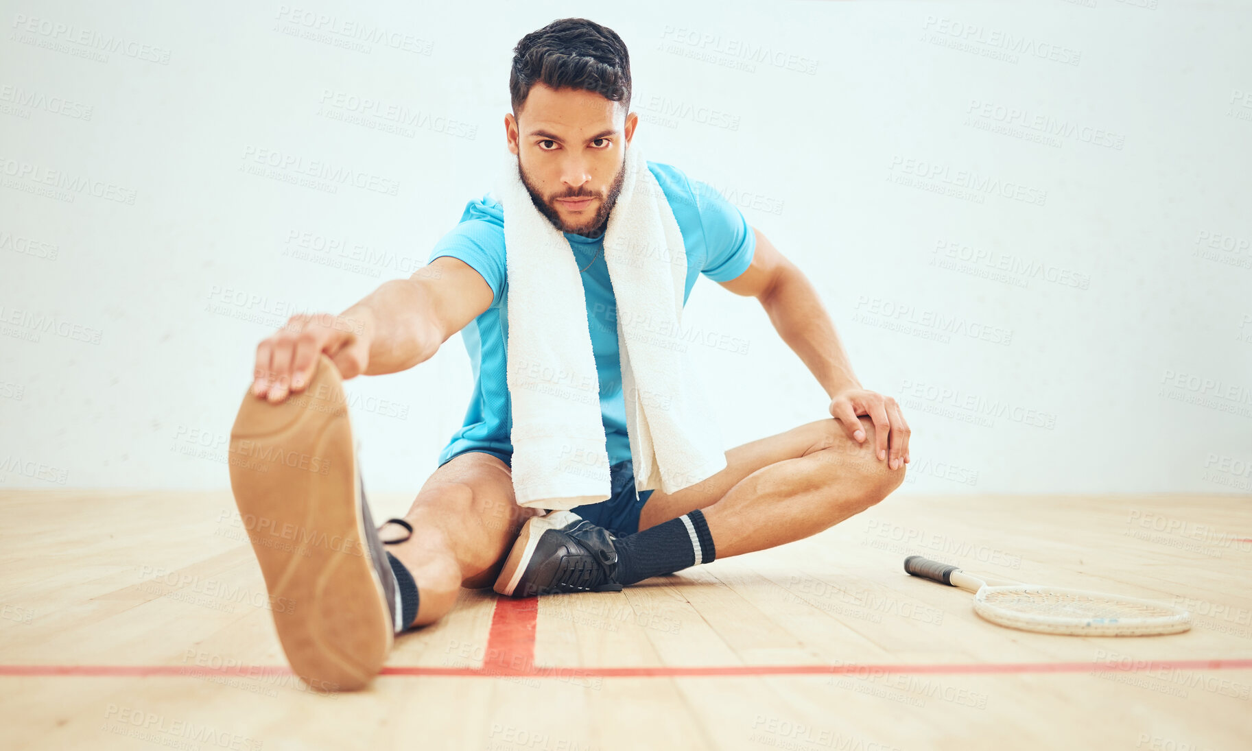 Buy stock photo Full length of squash player stretching and looking focused before playing court game with copyspace. Fit active hispanic athlete sitting alone and getting ready for training practice in sports centre
