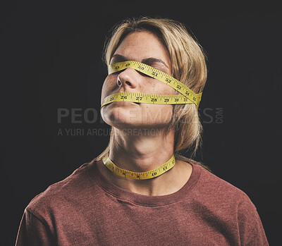 Buy stock photo Face, tape measure and stress with an anorexia woman in studio on a dark background for mental health and eating disorder. Sick, hunger and weight with a female struggling with society body pressure