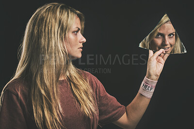 Buy stock photo Suicide, mental health and mirror with a woman looking at her reflection in a piece of glass in studio on a dark background. Bipolar, schizophrenia and depression with a sick female going mad
