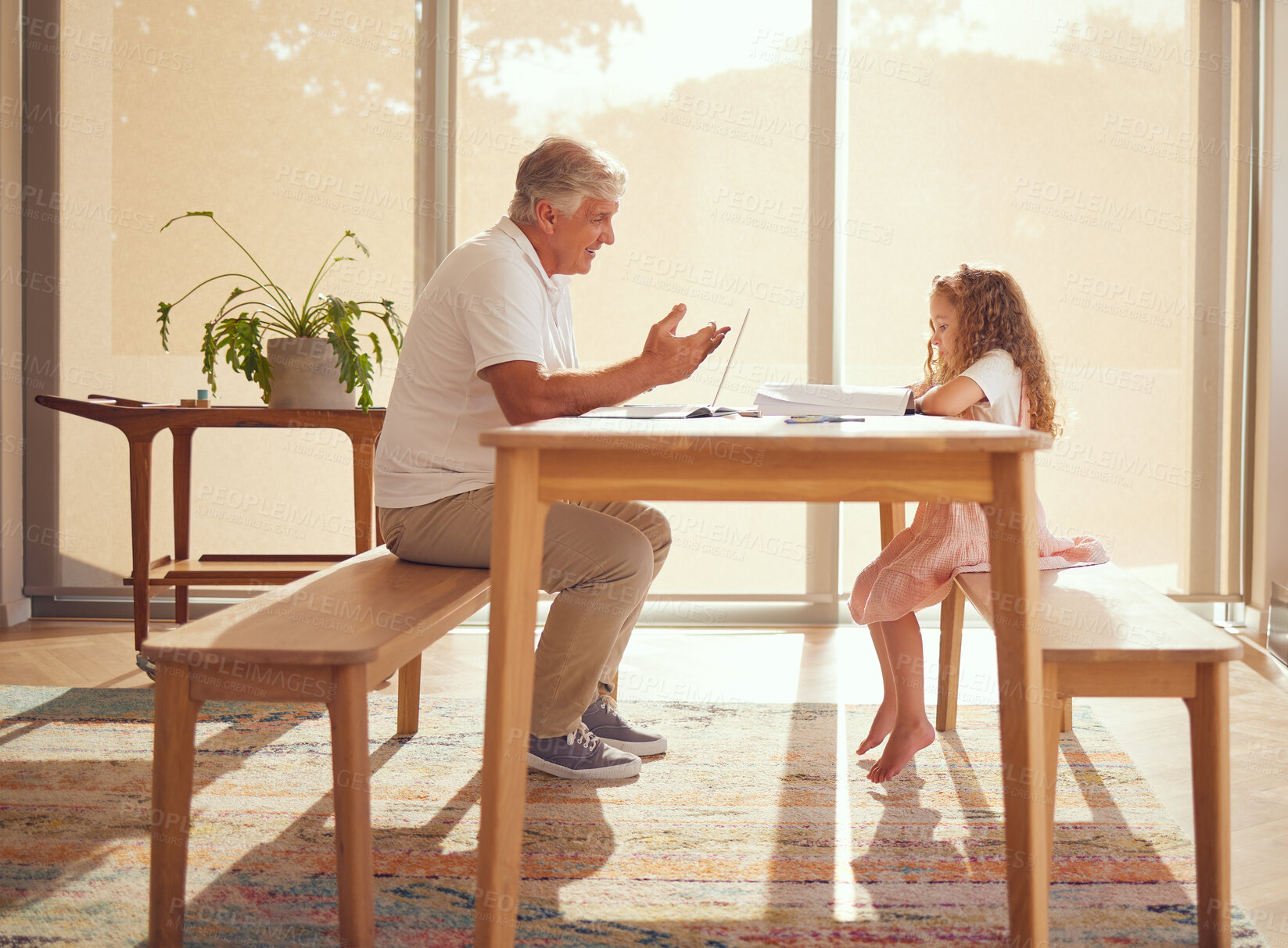 Buy stock photo Girl homework, internet research and grandfather helping a kid with school work with books at a table in their house. Child writing and learning education in notebook with elderly person on laptop
