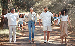 Big family walking in park holding hands for love, support and care on summer travel vacation in forest nature. Wellness, health and child development with grandparents and children or kids in woods