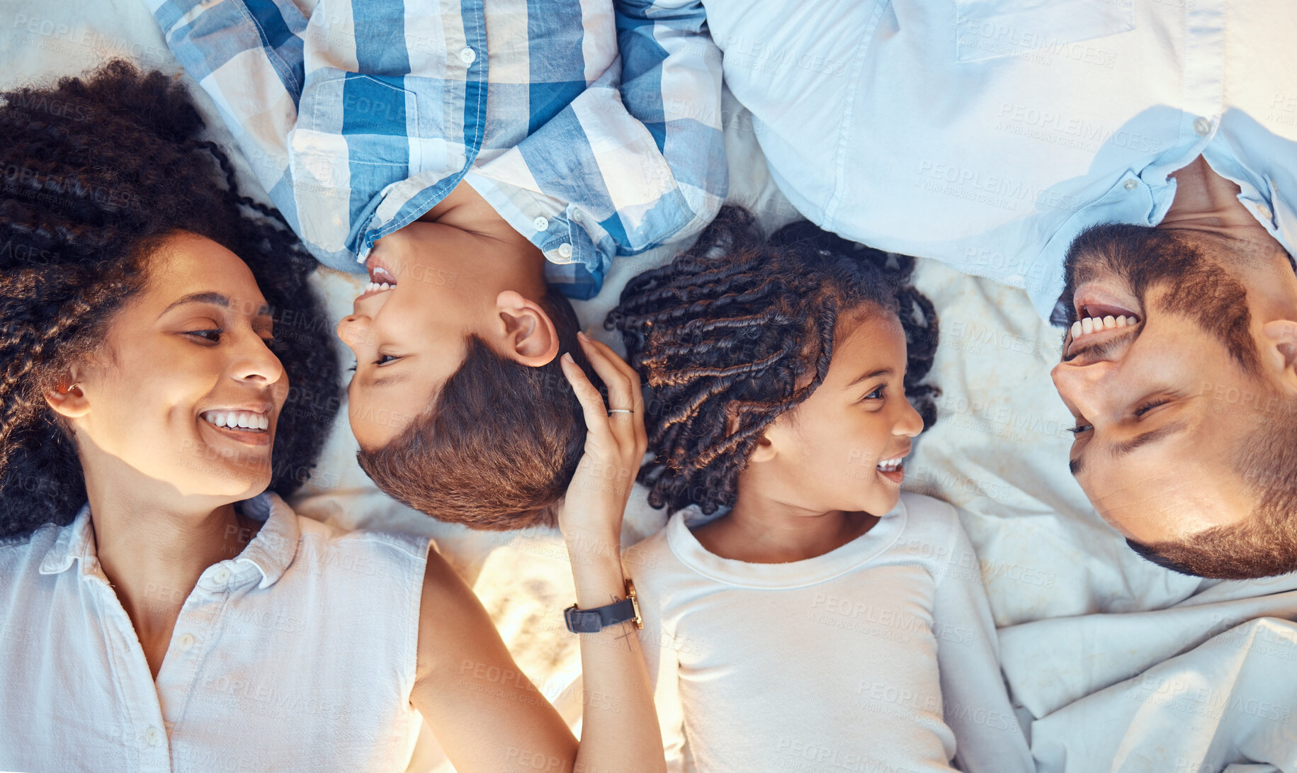 Buy stock photo Love, relax and happy family in bed, laughing, bonding and resting in their bedroom together from above. Black, cheerful and young parents enjoying time with their kids, conversation and sweet moment