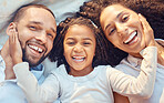 Family, parents and girl smile in bed for happy closeup together to relax together while laughing. Mother, dad and kid show happiness, love and fun for comic, funny or silly joke on blanket in house