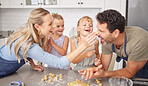 Happy family play with food cookies in kitchen with funny parents and girl children for home learning together, love and holiday celebration. Mother, father or fun people baking or cooking with kids