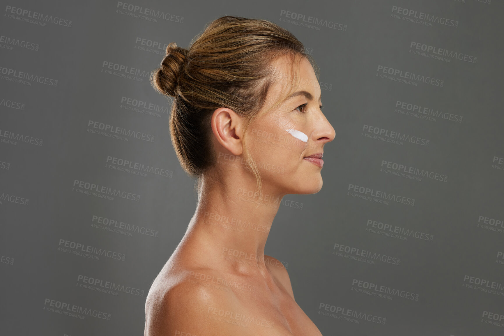 Buy stock photo Beauty, face and skin with a woman using antiaging cream in studio on a gray background with mockup. Skincare, treatment and body care with a beautiful female advertising healthcare from the side