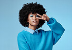 Portrait, young and black woman shows peace sign with blue studio background, afro and stylish look. Girl, lady and female with afro confident, relax and casual or funky dressed for fun day outside. 