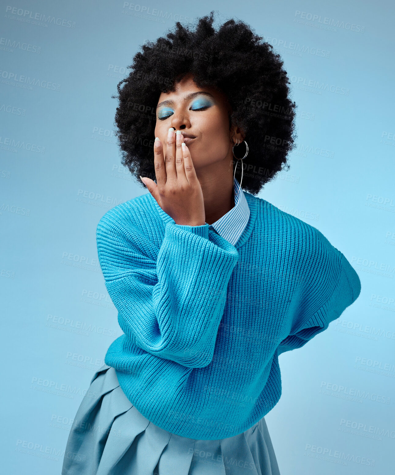 Buy stock photo Girl, blue and background with clothes for fashion with hand, face and kiss in studio with afro. Happy, model and fingers on lips for makeup, hair and beauty with azure color backdrop in Los Angeles