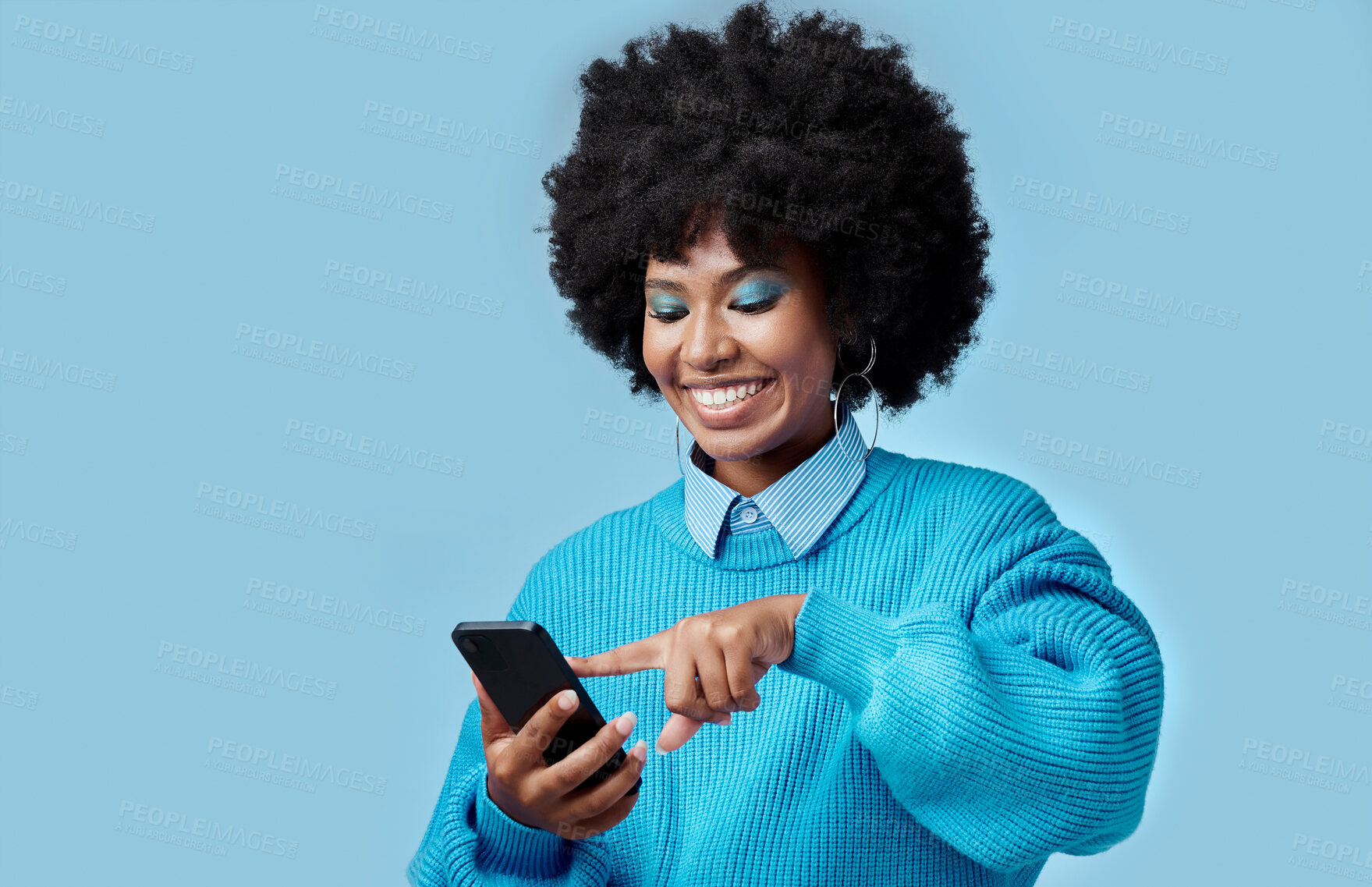 Buy stock photo Happy, phone and black woman reading a blog on an internet website in a studio with mockup space. Happiness, smile and african girl networking on social media on as smartphone with a blue background.
