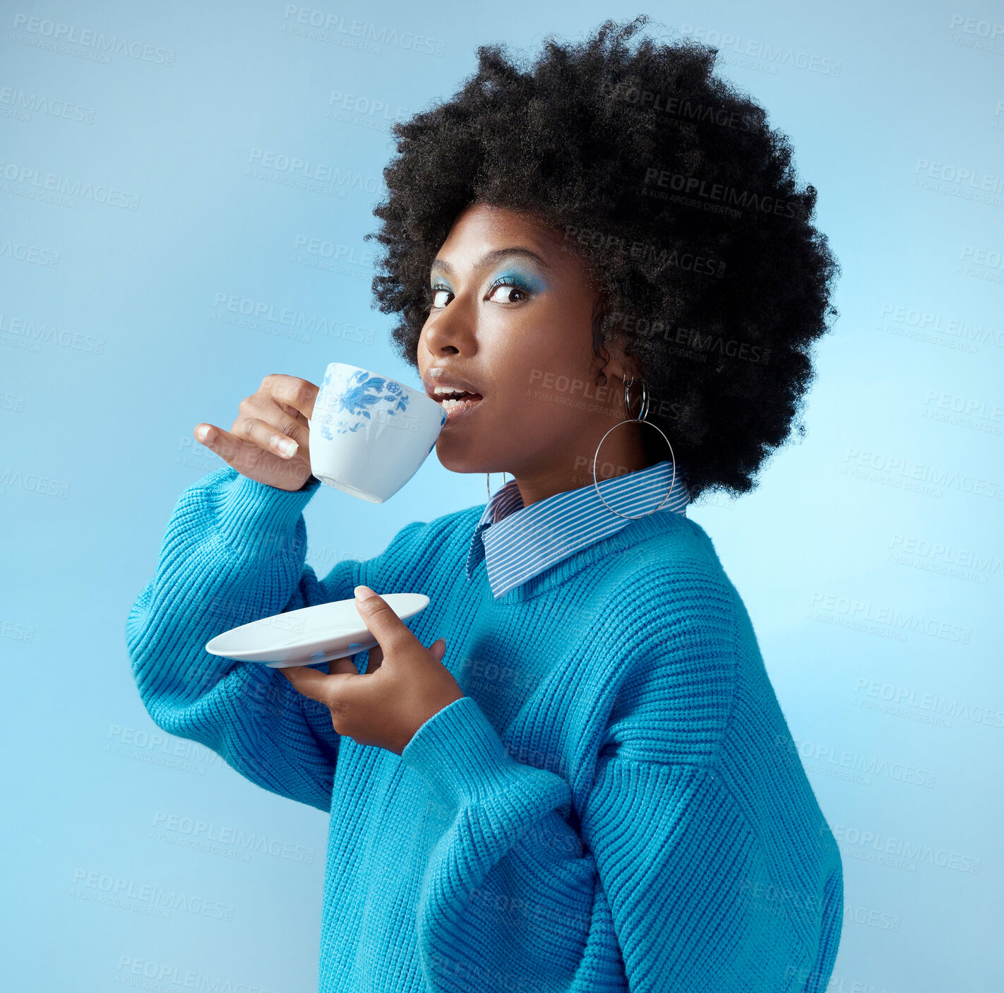 Buy stock photo Afro hair, tea cup and black woman with fashion, style and trend clothes on blue background in studio with bold makeup cosmetics. Portrait, gossip and beauty model with wow or surprise face and drink