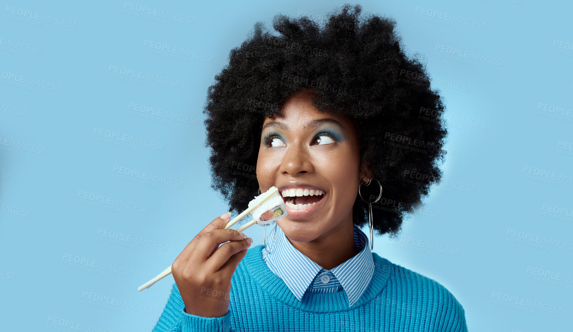 Buy stock photo Happy, food and black woman with sushi in a studio eating with japanese chopsticks with mockup space. Healthy meal, smile and african girl with a afro enjoying delicious sashimi with blue background.