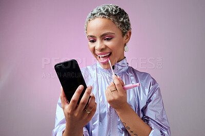 Buy stock photo Fashion, phone and woman using lipstick in studio for beauty, makeup and mouth cosmetics routine alone. Social media influencer applying pink lip gloss for selfcare against a grey studio background