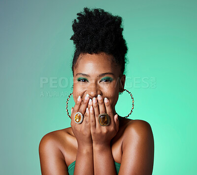 Buy stock photo Beauty, green fashion and makeup with a black woman laughing in studio on a wall background. Portrait, happy and funny with an attractive female joking inside while her hands are on her face