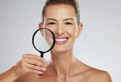 Buy stock photo Face, skincare and mature woman with magnifying glass for analysis of skin against a grey mockup studio background. Portrait of an elderly model doing facial inspection for wellness and beauty