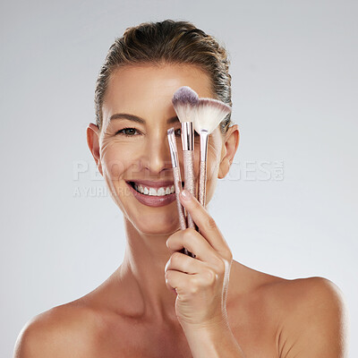 Buy stock photo Mature, model and brush for makeup in hand by face with happiness for cosmetic, beauty or skincare portrait. Woman, smile and powder happy against studio backdrop for skin health, care and wellness