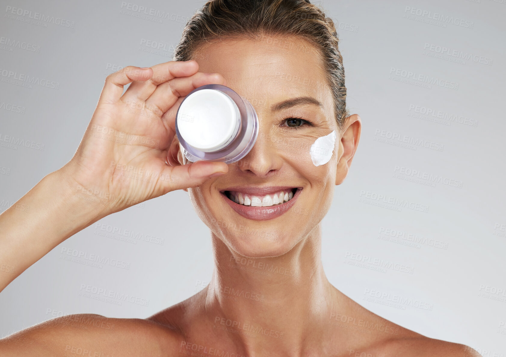 Buy stock photo Face cream, skincare and portrait of a mature woman in a studio standing by gray background. Happy, smile and healthy lady doing beauty facial treatment with a clean, self care and wellness lifestyle