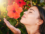 Beauty woman, smelling flowers and spring season in a garden or nature park to relax and smell tropical flower on a tree outside. Smile of a happy female enjoying her vacation holiday in Hawaii 