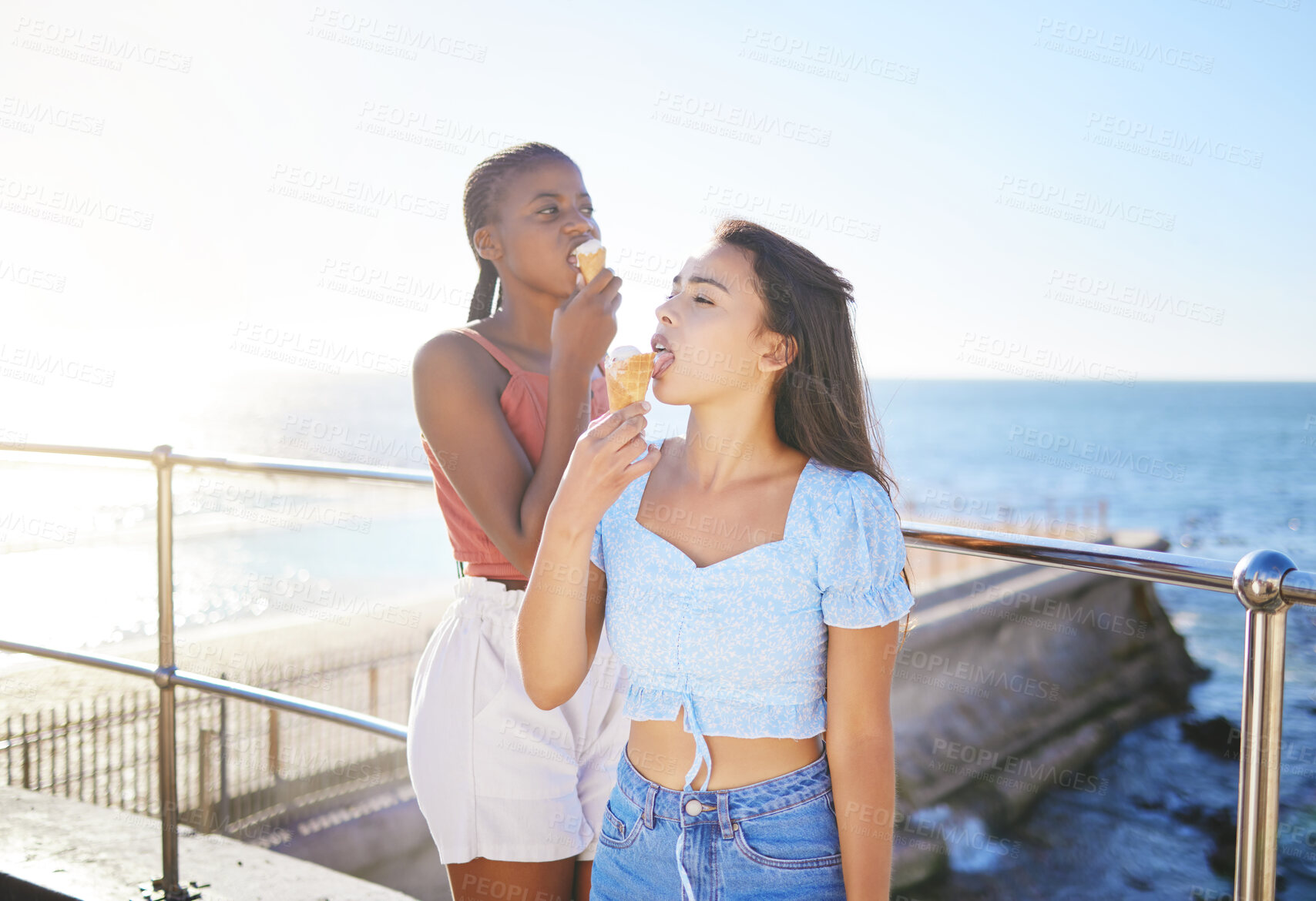 Buy stock photo Girl friends and eating ice cream at the beach together on summer sunshine holiday break in Italy. Carefree and satisfied women relax with tasty Italian dessert cone on European ocean vacation.