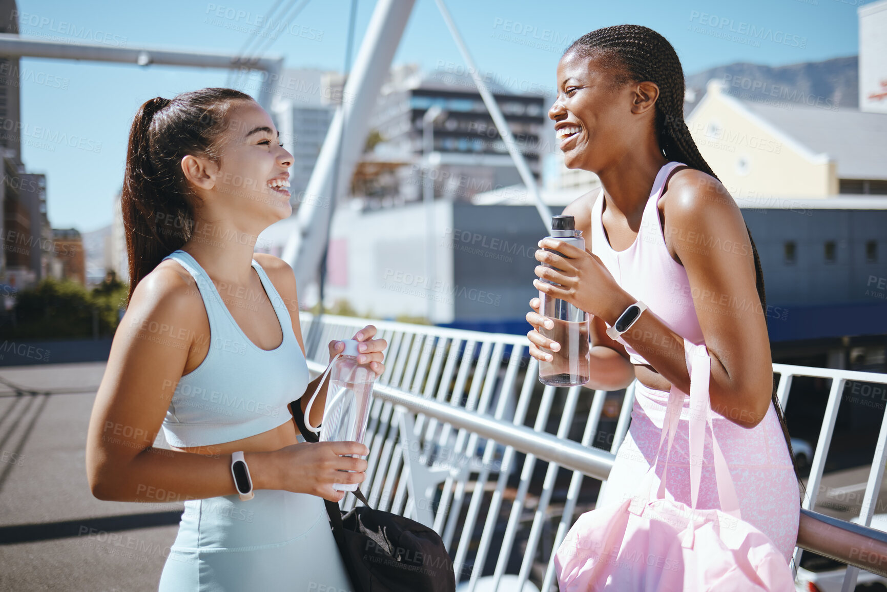 Buy stock photo Diversity, fitness and friends laughing while drinking water to hydrate after training, exercise and running outdoors in USA. Smile, healthy and happy black woman enjoys a funny joke with Latino girl