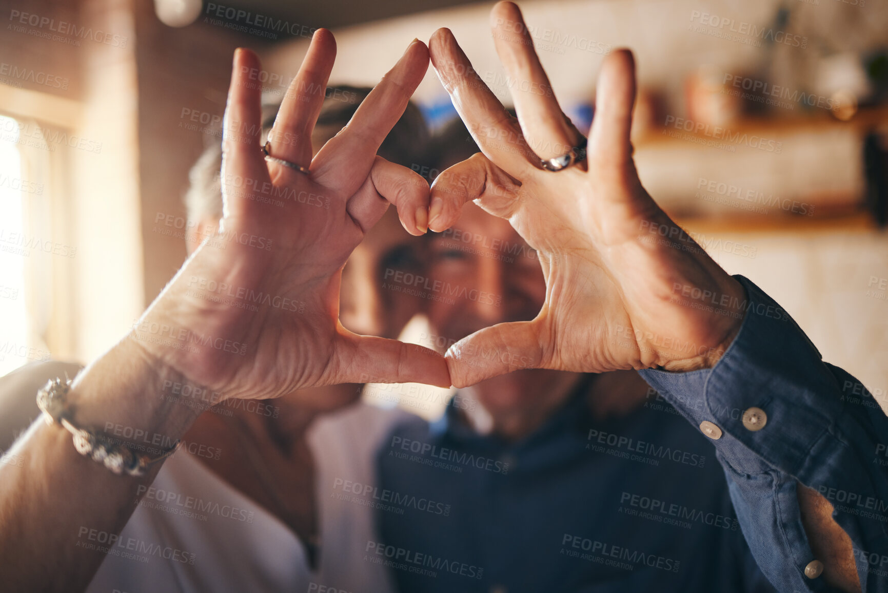 Buy stock photo Love, hands and heart sign with senior couple relax and bonding in their home together, cheerful and in love. Support, soulmate and loving man and woman sharing romantic moment and enjoy relationship