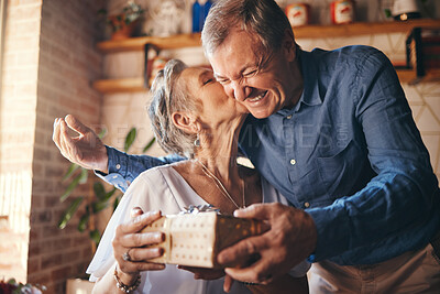 Buy stock photo Elderly, couple and happy with gift, surprise and kiss on face together in home. Man, woman and retirement show love, romance and happiness giving present for anniversary, birthday or mothers day