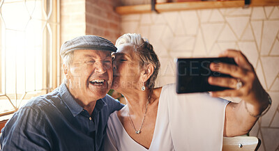 Buy stock photo Love, phone and selfie with elderly couple kiss and relax in their home together, laughing and bonding. Photography, retirement and seniors enjoying retired lifestyle and romance in their living room