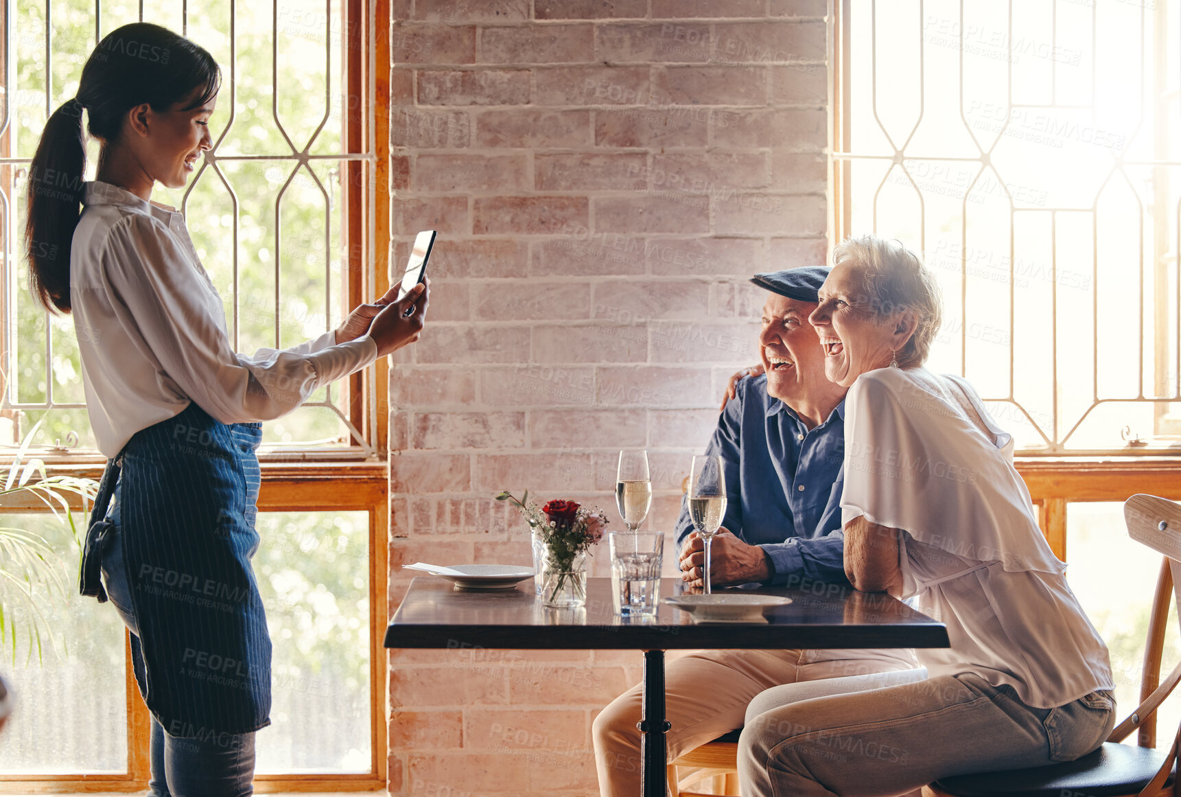 Buy stock photo Photograph, restaurant and date with a senior couple in celebration of an anniversary and waitress using a phone. Service, romance and travel with a man and woman tourist posing for a picture
