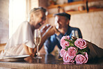 Love, celebration and foreground of roses for couple marriage anniversary with champagne for toast. Romantic, happy and caring senior people in relationship commitment together enjoy intimate date.