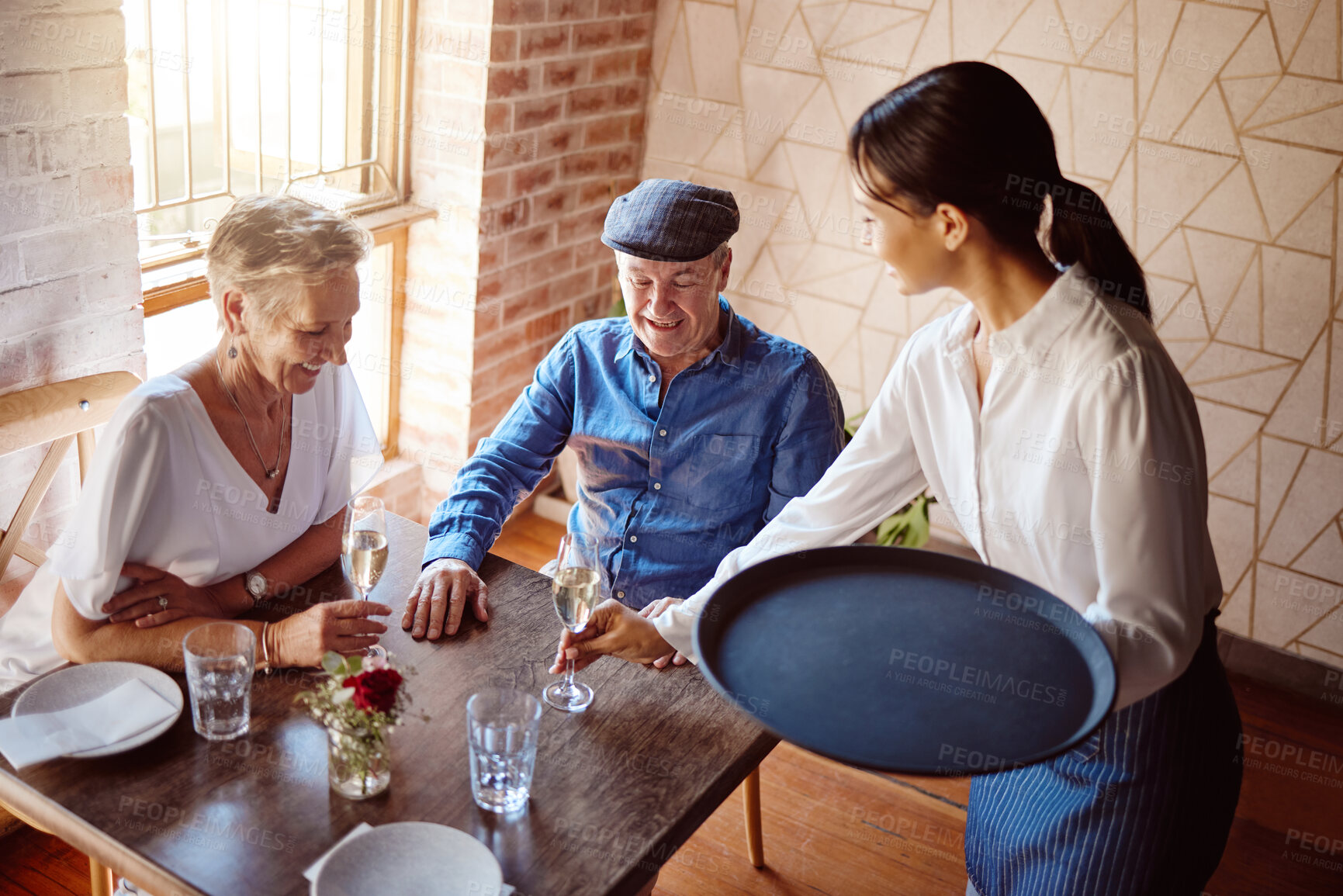 Buy stock photo Restaurant waitress, wine glass and service to happy couple for lunch celebration on fine dining date. Hospitality catering, alcohol champagne glasses and drinks menu order to senior customers table