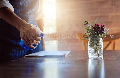 Buy stock photo Hand, cleaning and coffee shop with a woman spraying a table in her restaurant for hygiene and sanitizing. Flowers, cafe and surface with a female employee washing inside for service and cleanliness