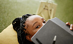 Black woman and student hiding face with notebook on casual college study lounge bean bag. Shy African university learner on studying rest break looking with lecture book to hide identity.