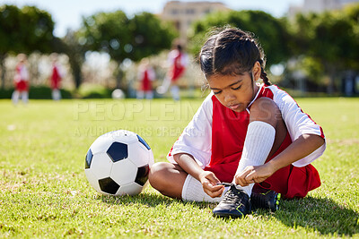 Buy stock photo Soccer, sports and girl tie her shoes in training practice for fitness, wellness and youth development. Exercise, workout and goals with child and soccer ball on football field for games match