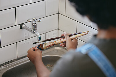 Paint, water and artist cleaning paintbrush under a tap or faucet. Clean, painter and creative woman washing her brushes with hands in the sink in her studio. Clean up after painting artwork project