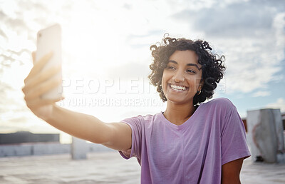 Buy stock photo Phone, selfie and social media with a woman taking a photograph outside in the city with a flare sky in India. Happy, smile and picture with an attractive young female posing on a rooftop